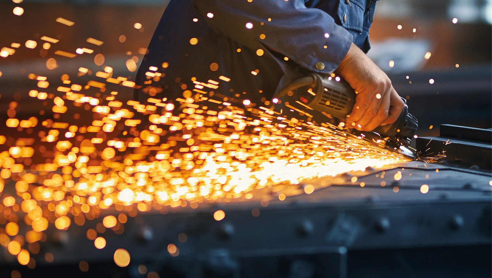 Bearbeitung eines Metallbauteils mit einem Winkelschleifer in der Produktion.