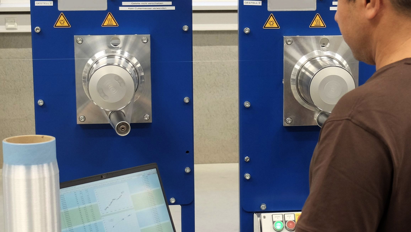 Person bedient eine industrielle Spinnereimaschine und überwacht Prozessdaten auf einem Bildschirm in einer Produktionsumgebung.